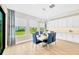 Dining room with modern light fixture, wood floors, large windows, and a table with blue chairs at 17804 Brewster Grn, Lutz, FL 33559