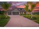 Beautiful home with a stone facade and palm trees, captured during a vibrant sunset at 17804 Brewster Grn, Lutz, FL 33559