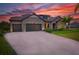 Charming home featuring a 3-car garage, stone accents, and a well-manicured lawn at sunset at 17804 Brewster Grn, Lutz, FL 33559