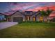 Charming home featuring a 3-car garage, stone accents, and a well-manicured lawn at sunset at 17804 Brewster Grn, Lutz, FL 33559