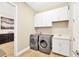 Functional laundry room with modern washer and dryer, white cabinets, and a convenient sink at 17804 Brewster Grn, Lutz, FL 33559