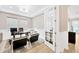 Well-lit office features an open door, a tray ceiling with a chandelier, and a plush rug under the desk at 17804 Brewster Grn, Lutz, FL 33559