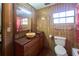 Bathroom features a window, toilet, vanity, mirror, lighting, and tiled walls and floors at 18121 Geraci Rd, Lutz, FL 33548