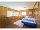 Cozy bedroom with wood paneled walls, a large window, and a comfortable bed with accent pillows at 18121 Geraci Rd, Lutz, FL 33548