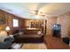 Cozy living room with a stone accent wall, paneled walls, ceiling fan, and a comfortable brown sofa at 18121 Geraci Rd, Lutz, FL 33548