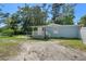 Charming light blue single-story home with a covered porch, gravel drive, and a fenced yard at 19496 Wildwood Dr, Brooksville, FL 34601