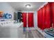 Laundry room with white washer and dryer, storage, and red curtains, offering functionality at 19496 Wildwood Dr, Brooksville, FL 34601