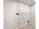 Laundry room featuring tile floor, a white door, grey walls, and overhead wire shelving at 20423 Symphony Pl, Venice, FL 34293