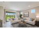 Inviting living room featuring plush sofas, a stylish coffee table, and large glass door that leads to an outdoor area at 20423 Symphony Pl, Venice, FL 34293