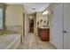 An ensuite bathroom featuring double sinks, a soaking tub, tile flooring, and a walk-in closet entrance at 2387 Bartolo Dr, Land O Lakes, FL 34639