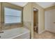 Bathroom showcasing a tub and toilet; featuring tile flooring and a window for natural light at 2387 Bartolo Dr, Land O Lakes, FL 34639