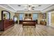 A spacious primary bedroom featuring a tray ceiling, wood floors, and an ensuite bathroom entrance at 2387 Bartolo Dr, Land O Lakes, FL 34639