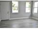 A brightly lit room with three windows, a white door, light gray walls, and light gray laminate flooring at 2504 E 28Th Ave, Tampa, FL 33605