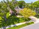 Aerial view of a home with mature trees, a brick driveway, and a well-kept lawn in a peaceful neighborhood at 2550 Rolling View Dr, Dunedin, FL 34698