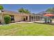 A spacious backyard featuring a pool with a screened enclosure, a lush green lawn, and a cozy outdoor seating area at 2550 Rolling View Dr, Dunedin, FL 34698