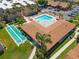 Aerial view showcasing a community pool, shuffleboard courts, and a complex's roofline at 2640 Woodgate Ln # F6, Sarasota, FL 34231