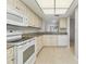 Well-lit kitchen featuring white cabinets, appliances, granite countertops, and tile flooring at 2640 Woodgate Ln # F6, Sarasota, FL 34231