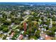 An aerial view of a home in a mature residential neighborhood with swimming pool, lush trees, and bay water in the distance at 2662 Oakbrook Dr, Largo, FL 33770