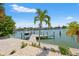 Beautiful waterfront home featuring a private dock, lush palm trees, and serene water views on a sunny day at 3021 Alton Dr, St Pete Beach, FL 33706