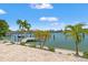 Beautiful view of a waterfront backyard with a private dock, lush palm trees, and tropical landscaping at 3021 Alton Dr, St Pete Beach, FL 33706