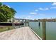 View of the wooden dock featuring a boat lift with a boat against a blue sky and beautiful waterfront view at 3021 Alton Dr, St Pete Beach, FL 33706