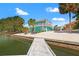 The two-story home with a balcony overlooks the waterfront, with palm trees dotting the property and a white rock yard at 3021 Alton Dr, St Pete Beach, FL 33706