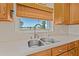 Close up of the kitchen sink area, featuring wooden cabinets, tile backsplash and a bamboo shade at 3021 Alton Dr, St Pete Beach, FL 33706