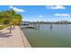 Beautiful waterfront featuring a dock, clear blue sky, calm water, and lush tropical landscaping at 3021 Alton Dr, St Pete Beach, FL 33706