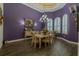 Formal dining room featuring dark purple walls, wood floors, chandelier, and ample natural light through shuttered windows at 304 Hawk Talon Dr, Lithia, FL 33547