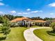 Stunning Mediterranean-style home with a circular driveway, lush landscaping, and a terracotta roof at 304 Hawk Talon Dr, Lithia, FL 33547