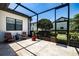 A screened-in patio features travertine tile, Adirondack chairs, and a small dog door at 304 Hawk Talon Dr, Lithia, FL 33547