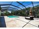 A screened-in pool is surrounded by travertine tile, and has an outdoor daybed with umbrella at 304 Hawk Talon Dr, Lithia, FL 33547