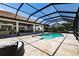 A screened pool is surrounded by travertine tile, with an outdoor kitchen and covered seating nearby at 304 Hawk Talon Dr, Lithia, FL 33547