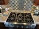 Stainless steel Thermador gas cooktop with tile backsplash and granite countertop at 324 6Th Ave, Indian Rocks Beach, FL 33785