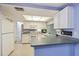 Well-lit kitchen with white cabinetry, ample counter space, and a pass-through to the adjoining dining area at 4017 Moog Rd, Holiday, FL 34691