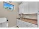 Well-lit laundry room equipped with white cabinets, sink, counter space, and a modern washing machine at 4610 Alexandria Ct, Palmetto, FL 34221