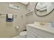 Bathroom featuring a white vanity, modern fixtures, a decorative round mirror, and a toilet at 4939 Floramar Ter # 504, New Port Richey, FL 34652