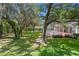 Scenic backyard with mature trees and lush lawn, featuring a glimpse of the screened-in pool at 5017 Muir Way, Lithia, FL 33547