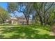 Expansive backyard with lush green lawn and mature trees surrounding a screened in pool area at 5017 Muir Way, Lithia, FL 33547