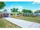 A charming home featuring a well-manicured lawn, covered carport, and coral colored front door that make for an inviting curb appeal at 5365 Flamingo Dr, St Petersburg, FL 33714