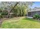 Lush backyard with mature trees, a well-maintained lawn, and a screened-in porch at 614 Fayette S Dr, Safety Harbor, FL 34695
