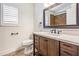 Well-lit bathroom featuring a dark wood vanity, a white toilet, and a window with plantation shutters at 614 Fayette S Dr, Safety Harbor, FL 34695