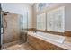 Bright bathroom featuring a glass-enclosed shower and a soaking tub with stone detailing below a window at 614 Fayette S Dr, Safety Harbor, FL 34695
