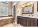 Bathroom featuring a dual sink vanity, tiled flooring, a tub, and a window providing natural light at 614 Fayette S Dr, Safety Harbor, FL 34695