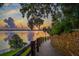 Scenic waterfront view with lush greenery, a stone walkway, and a stunning sunset reflecting on the calm water at 614 Fayette S Dr, Safety Harbor, FL 34695