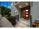 Contemporary home's entry showcasing a vibrant red door and manicured garden bed at 6904 S Macdill Ave # 1, Tampa, FL 33611