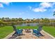 Picturesque backyard with a fire pit, Adirondack chairs, and a tranquil lake view at 7023 Montauk Point Xing, Bradenton, FL 34212