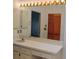 Bathroom vanity featuring a large mirror with Hollywood-style lighting and white cabinets at 7085 Sunset S Dr # A, St Petersburg, FL 33707