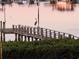 A heron stands on a weathered wooden dock over the calm water at sunrise at 7085 Sunset S Dr # A, St Petersburg, FL 33707