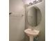 This bathroom features a pedestal sink, oval mirror, chrome towel rack, and soft green walls at 8531 Trail Wind Dr, Tampa, FL 33647